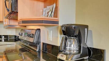 Een keuken met een koffiezetapparaat, een fornuis en een magnetron.