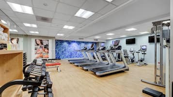 Un gimnasio con cintas de correr, elípticas y pesas libres.