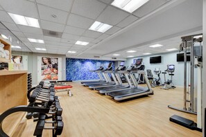 A gym with treadmills, elliptical machines, and free weights.