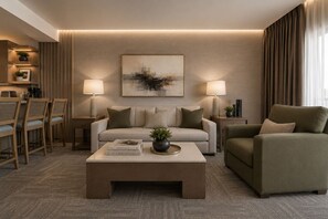 A modern living room with a sofa, armchair, coffee table, and lamps. There is a painting on the wall and a plant on the coffee table.