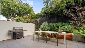 An outdoor patio with a barbecue grill, a table, and chairs. - Leafy Caulfield Townhouse - (pool, car park, BBQ) (Caulfield North)
