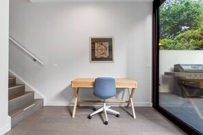Ein Zimmer mit einem Holztisch, einem Stuhl, einer Treppe und Blick auf einen Grill im Freien durch eine Glastür.