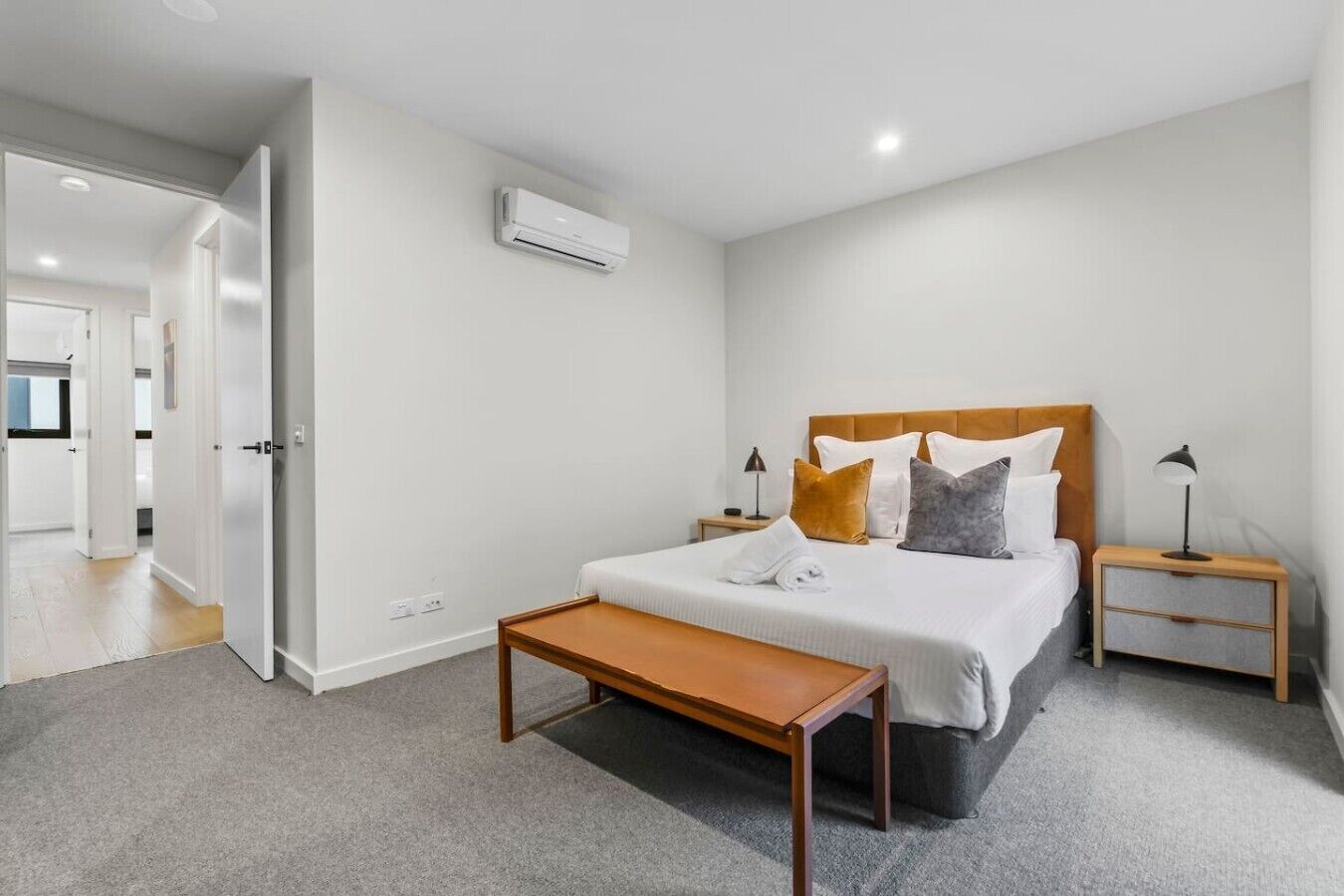Habitación de hotel con cama, mesitas de noche, un banco y un equipo de aire acondicionado.