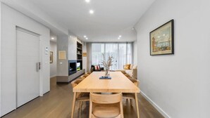 A modern living room with a dining table, sofas, and a fireplace. - Leafy Caulfield Townhouse - (pool, car park, BBQ) (Caulfield North)