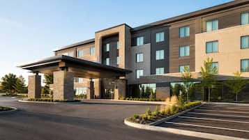 A multi-story hotel with a covered entrance and a parking lot.