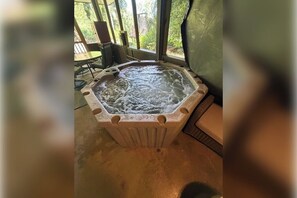 A hot tub in a room with a view of greenery outside. - Mountain Memories Gatlinburg Home Sleeps 9 NO Winding Roads (Gatlinburg)