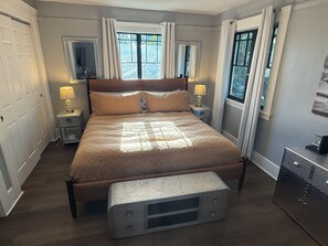 A bedroom with a bed, bedside lamps, a dresser, and a window with curtains. - Welcome to the Aviator - 1920's Craftsman Airplane Bungalow (Modesto)