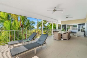 A covered outdoor area with lounge chairs, a dining table, and ceiling fans. - Tranquillity - Poolside Sanctuary & Rainforest Views (Smithfield)