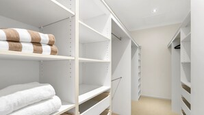 A walk-in closet with white shelving units, some with towels. - Tranquillity - Poolside Sanctuary & Rainforest Views (Smithfield)