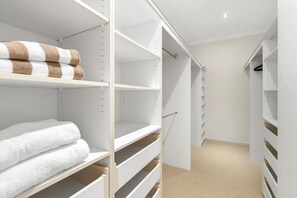 Ein begehbarer Kleiderschrank mit weißen Regaleinheiten, einige mit Handtüchern.