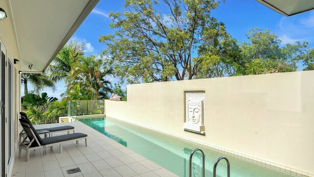 A swimming pool with lounge chairs, a Buddha statue, and a clear sky. - Tranquillity - Poolside Sanctuary & Rainforest Views (Smithfield)