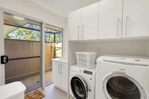 A laundry room with a washing machine, a dryer, and a drying rack. - Tranquillity - Poolside Sanctuary & Rainforest Views (Smithfield)