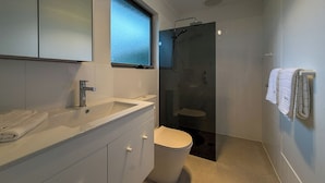 A modern bathroom with a large mirror, a sink, a toilet, and a shower. - Silver Sands Beach House (Aldinga Beach)