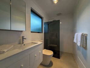 A modern bathroom with a large mirror, a sink, a toilet, and a shower. - Silver Sands Beach House (Aldinga Beach)