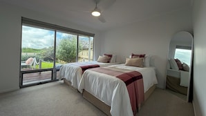 A bedroom with a bed, a ceiling fan, a large window, and a view of the outdoors. - Silver Sands Beach House (Aldinga Beach)