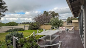 A deck with a barbecue area, outdoor furniture, and a view of the surrounding landscape. - Silver Sands Beach House (Aldinga Beach)