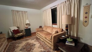 A living room with a sofa, a small table, a lamp, and a rug.