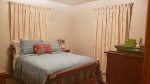 A bedroom with a bed, a nightstand, a lamp, and curtains.