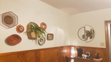 A wall with decorative items including a woven basket, a mirror, and a framed picture.