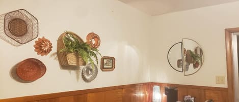 A wall with decorative items including a woven basket, a mirror, and a framed picture.