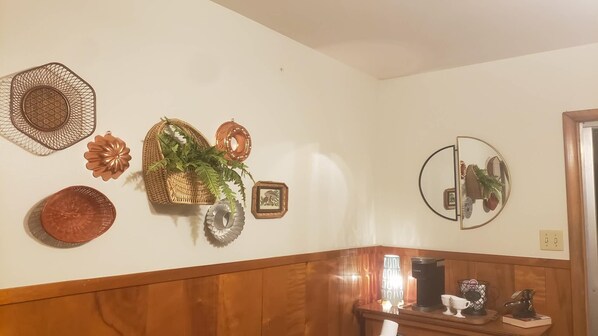 A wall with decorative items including a woven basket, a mirror, and a framed picture.