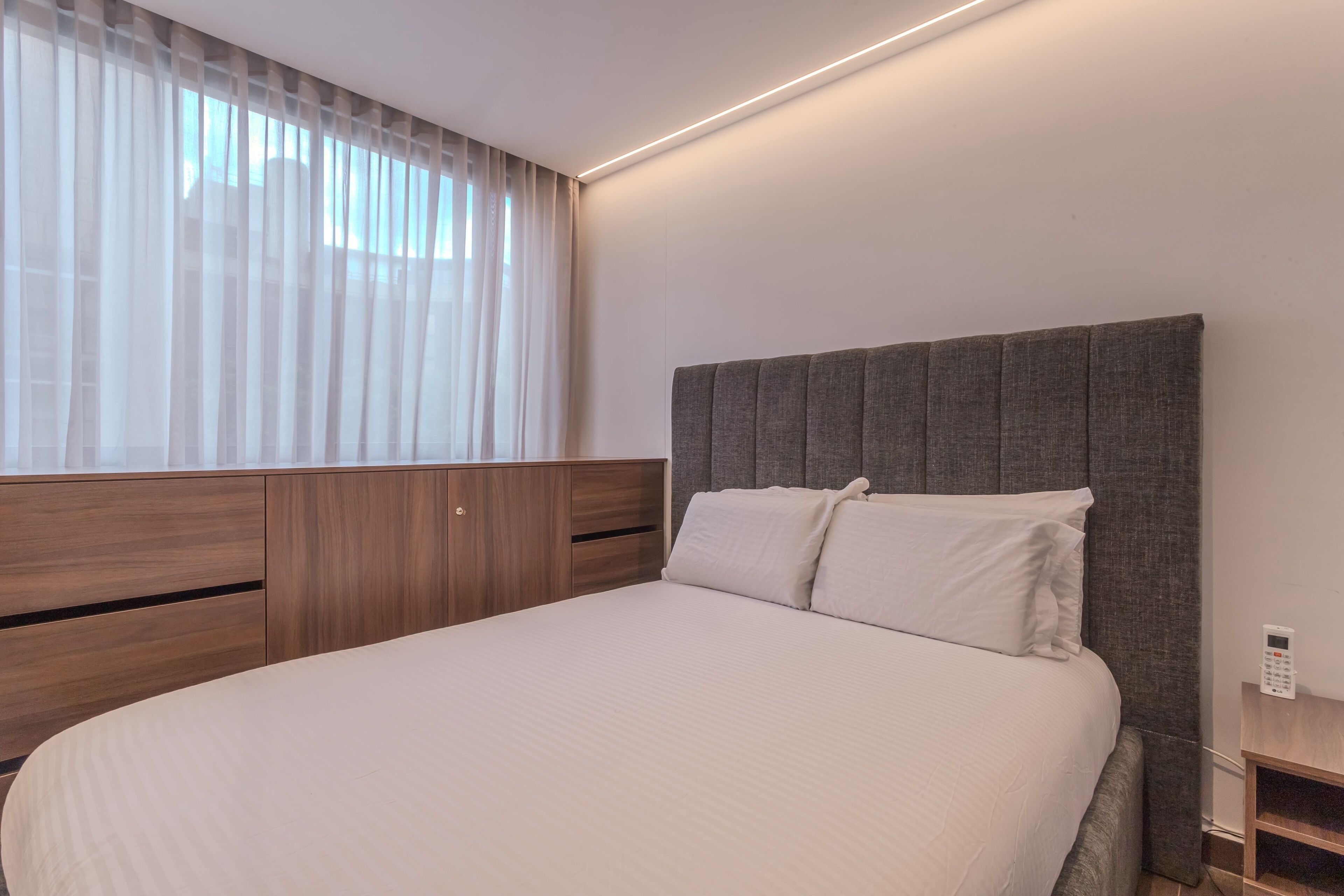 Une chambre moderne avec un grand lit, une tête de lit en bois et une table de chevet avec un téléphone.