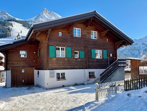 Un chalet en bois doté d’un balcon, d’un garage et d’un escalier menant à l’entrée.