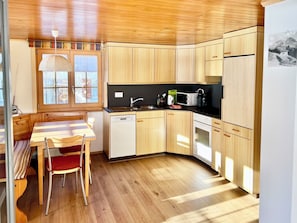 A compact kitchen with wooden cabinets, a dining table with chairs, and a window with a view of the outside. - Falkiport Schranz Appartement/Fewo, Bad, WC, 3 Schlafräume 4-Zimmerwohnung by Interhome (Adelboden)