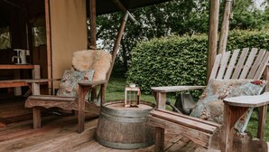 A rustic outdoor seating area with wooden furniture and a metal barrel. - Kampari - Luxe Safaritent - Titanic by Interhome (Delfstrahuizen)