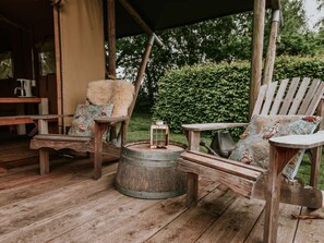 A rustic outdoor seating area with wooden furniture and a metal barrel. - Kampari - Luxe Safaritent - Titanic by Interhome (Delfstrahuizen)