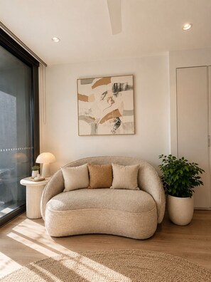 Un salon moderne avec un canapé, une plante en pot et un tableau abstrait accroché au mur.