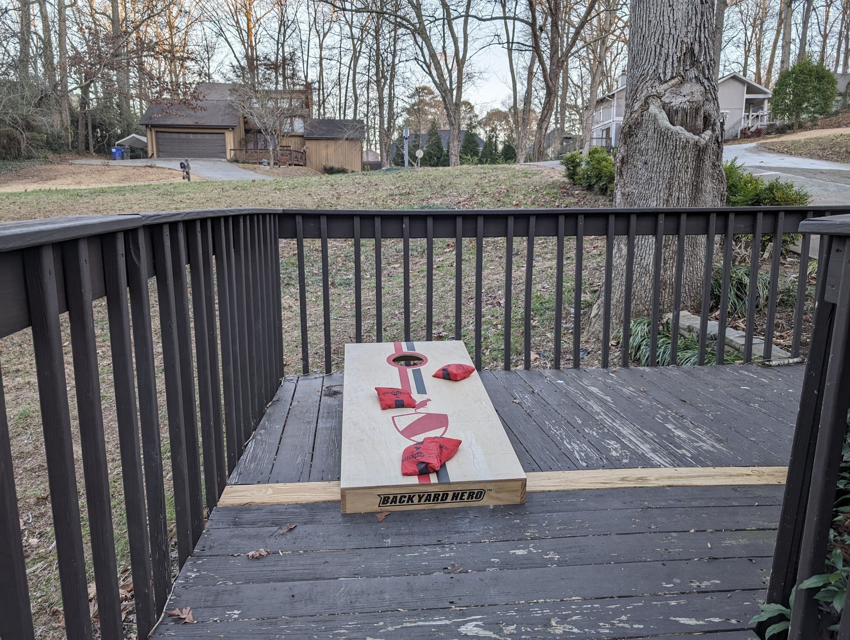 Une terrasse en bois avec une planche à l’arrière portant l’inscription « BACKYARD HERO™ » et un objet rouge posé dessus.