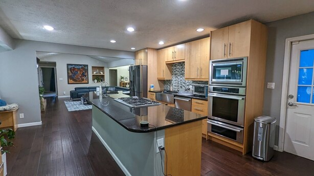 Una cocina moderna con una isla central, electrodomésticos de acero inoxidable y armarios de madera.
