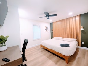 A bedroom with a bed, a desk, a chair, a ceiling fan, a window, and a wall-mounted lamp. - Custom Design, Kitchen King Beds Laundry Large TVs (Rome)