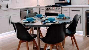 Una cucina moderna con mobili bianchi, piano cottura, forno e un tavolo da pranzo apparecchiato con ciotole e piatti blu.
