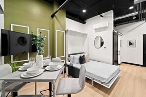 A modern hotel room with a dining area, a bed, a TV, and a mirror. - Walk to Petco Park | Gaslamp, Dining & Nightlife!! (San Diego)