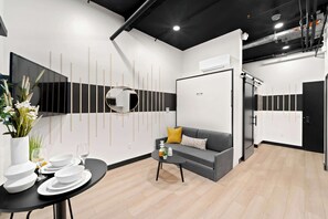 A modern kitchen with a grey sofa, a dining table set with white plates, and a black coffee table. - Make Memories Downtown | Walk to Petco Park & Fun! (San Diego)