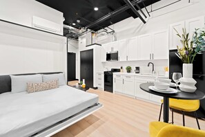 A modern apartment with a bed, kitchenette, and dining area. - Make Memories Downtown | Walk to Petco Park & Fun! (San Diego)