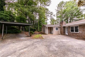 A residential property with a covered garage, a brick house, and a paved driveway. - Arcade Shuffleboard Poker Firepit Grill @ Battery (Marietta)