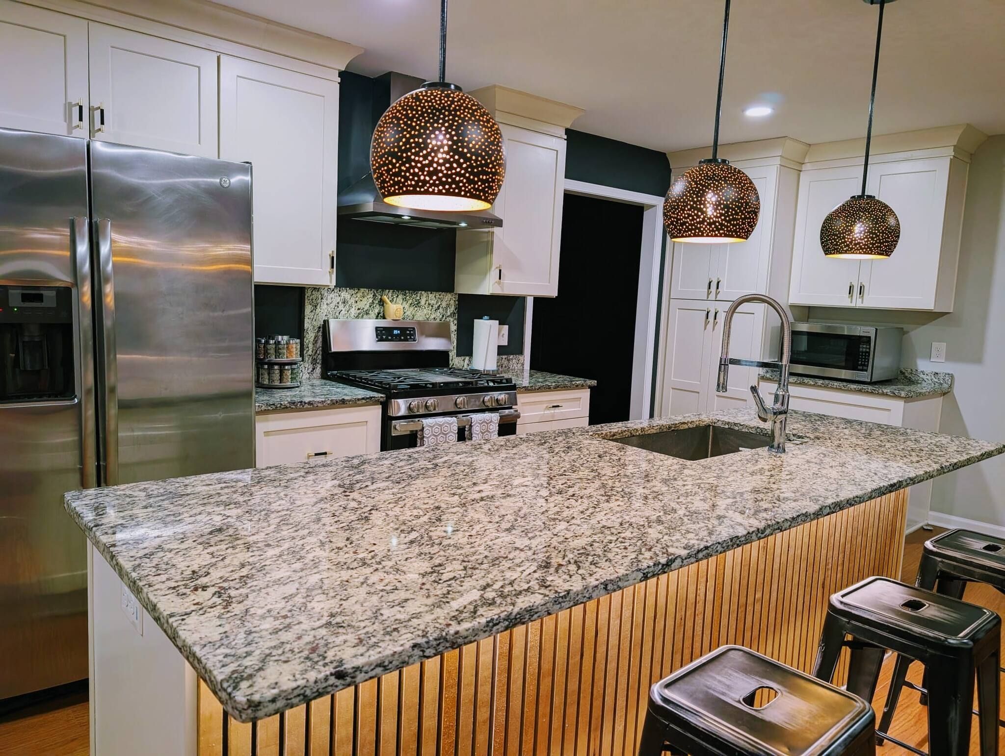 A modern kitchen with granite countertops, stainless steel appliances, and pendant lighting.