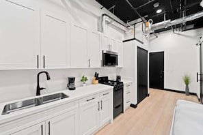 A modern kitchen with white cabinets, a black microwave, and a stove. - Live the Action | Walk to Petco Park Gaslamp & Fun (San Diego)