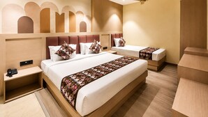 Habitación de hotel con una cama grande, dos mesitas de noche, un escritorio y un ventilador de techo.