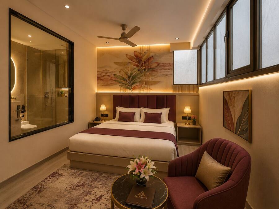 Habitación de hotel con una cama grande, una zona de estar con una silla, una mesa de centro redonda, un espejo grande y un ventilador de techo.