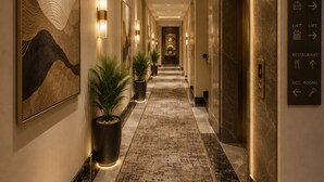 Un pasillo de hotel con indicaciones, una zona de recepción y un ascensor.