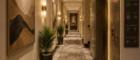 A hotel corridor with directional signs, a reception area, and a lift.