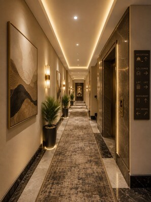 A hotel corridor with directional signs, a reception area, and a lift. - Purple Martin by AVSA Stayz (Amritsar)
