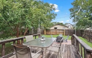 An outdoor patio with a table and chairs, surrounded by a wooden deck and a wooden fence. - Charming 2-bedroom house in beautiful College Station 2 miles from campus. (College Station)