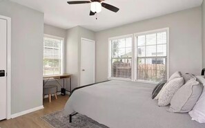 Une chambre à coucher avec un lit, un bureau et un ventilateur de plafond.