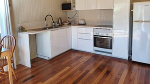A modern kitchen with white cabinets, a built-in oven, and a stainless steel sink.