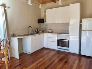 A modern kitchen with white cabinets, a built-in oven, and a stainless steel sink.